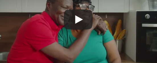 Image of an older Black man smiling and embracing a Black woman