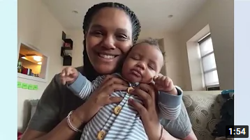 New mom, Erika smiles and is holding her sleeping baby. 