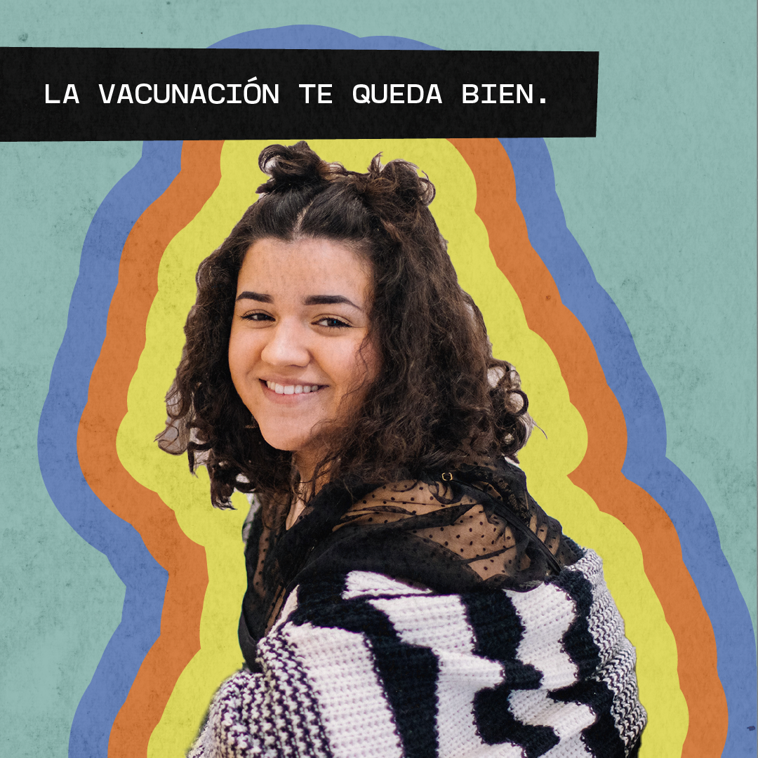Young woman smiling with a blanket wrapped around her shoulders. Message says in Spanish: "Vaccination looks good on you."