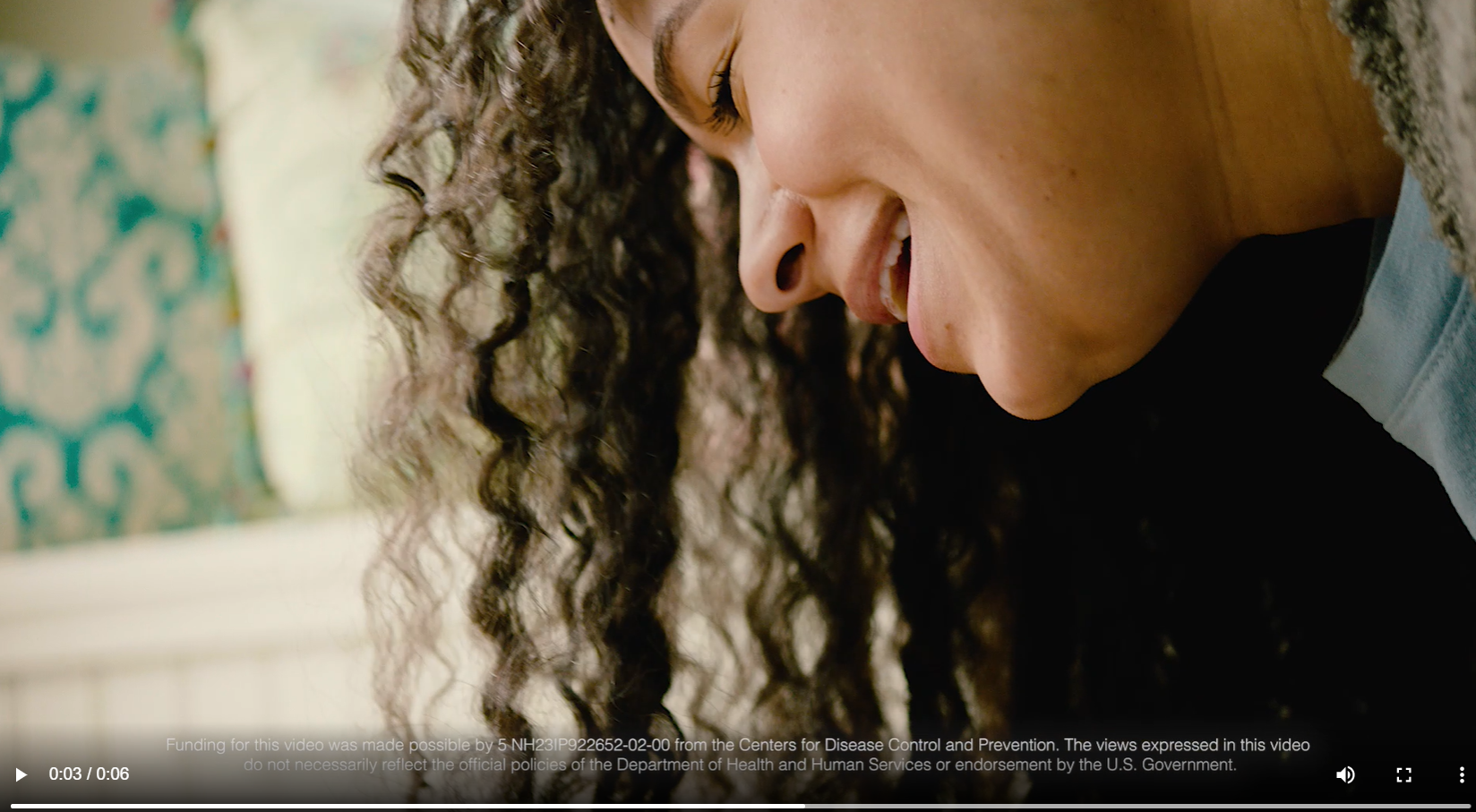 A Black woman smiles and looks down
