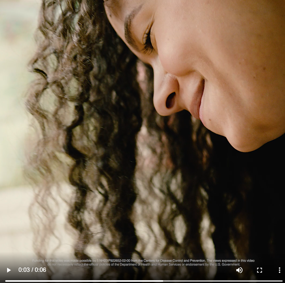 A Black woman smiles and looks down