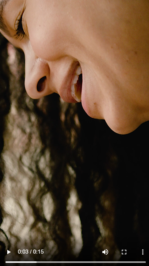 A Black woman smiles and looks down