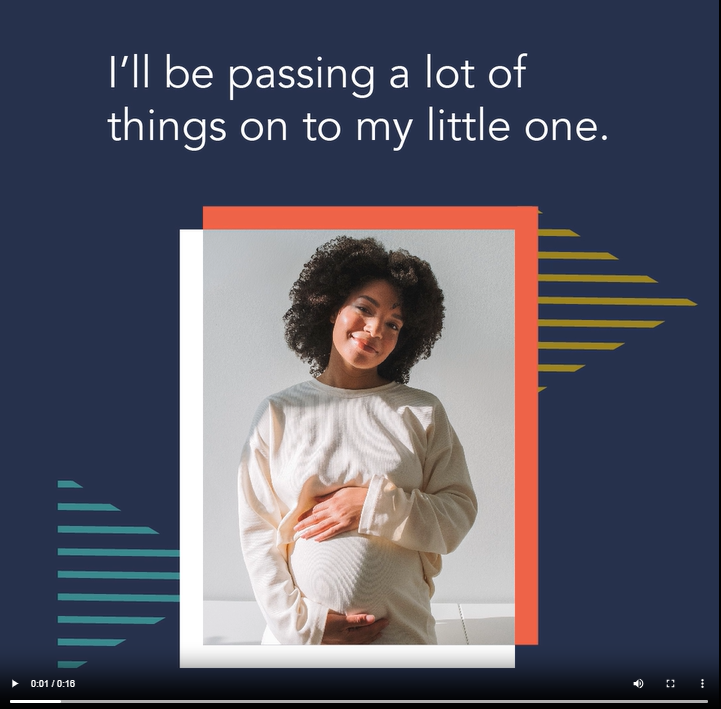 A Black pregnant woman smiles and places her hands over her stomach 