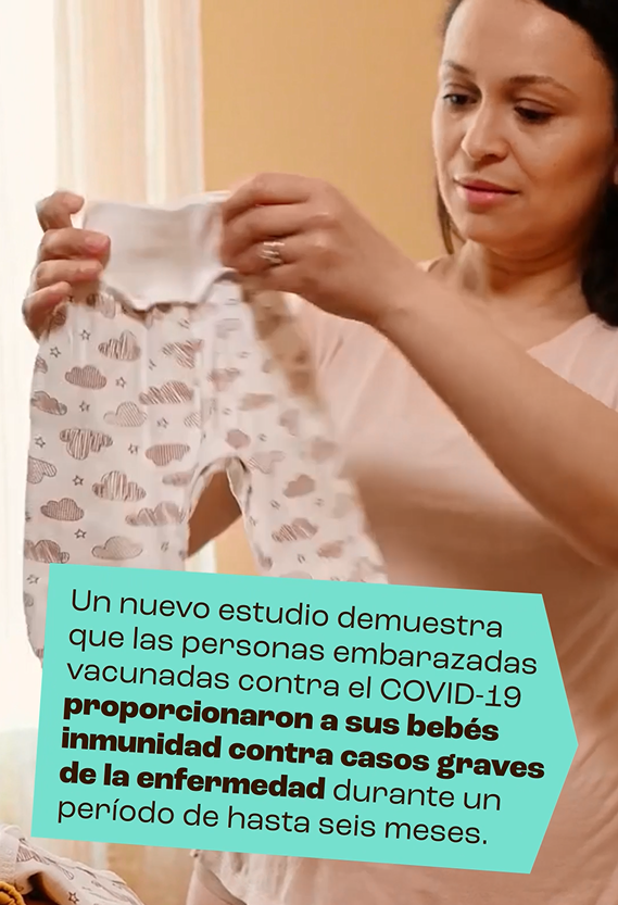 A woman holding an infant's onesie and smiling