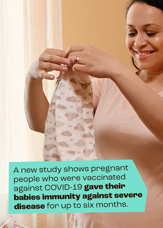 A woman holding an infant's onesie and smiling