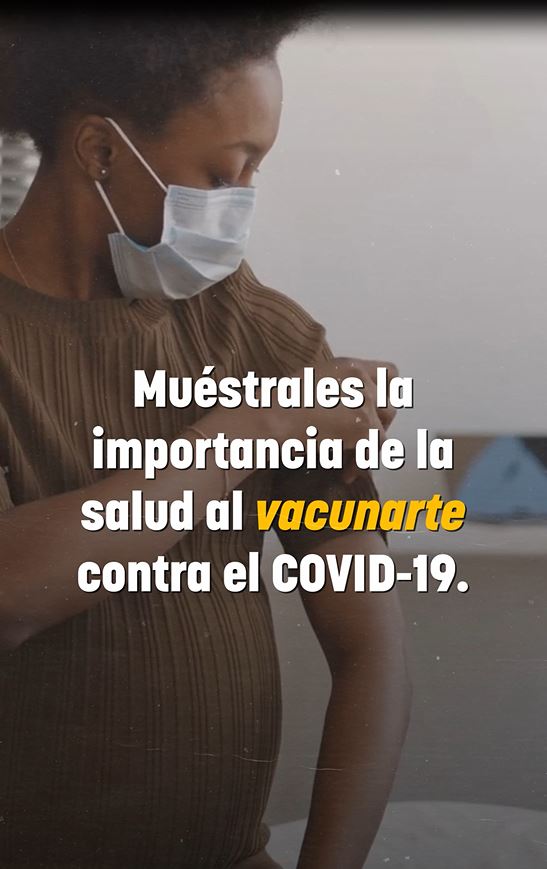 Image of a pregnant black woman wearing a mask and looking at a bandage on her arm