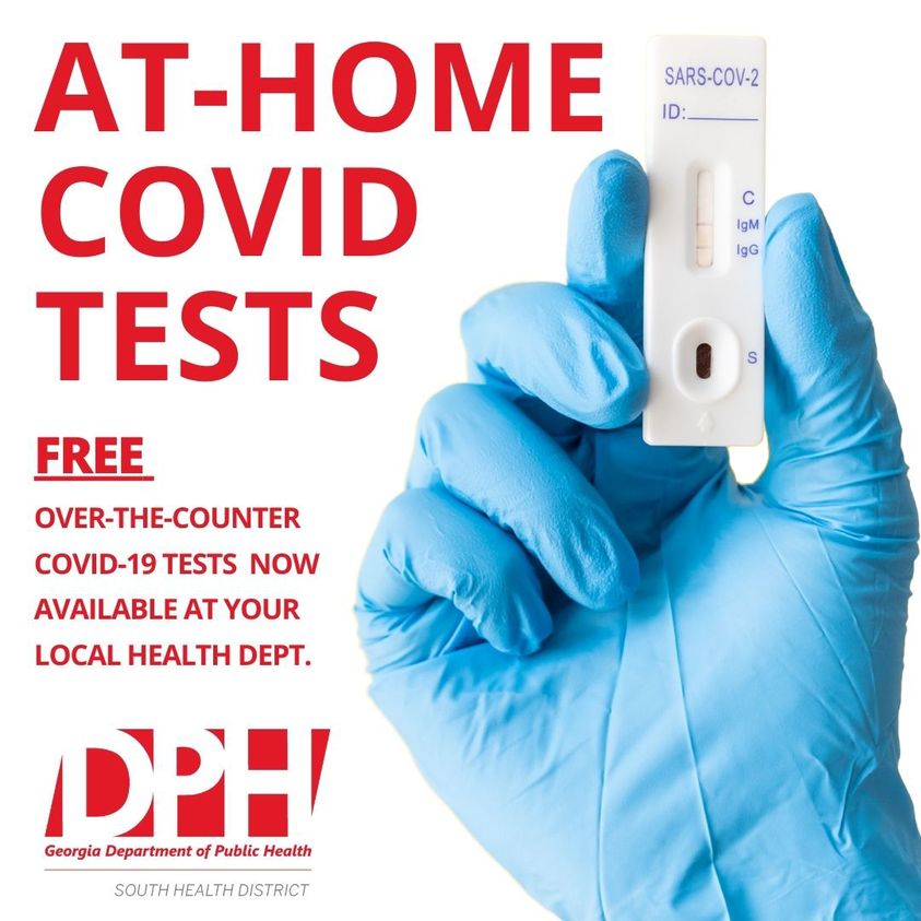 Gloved hand holds up an at home COVID test 