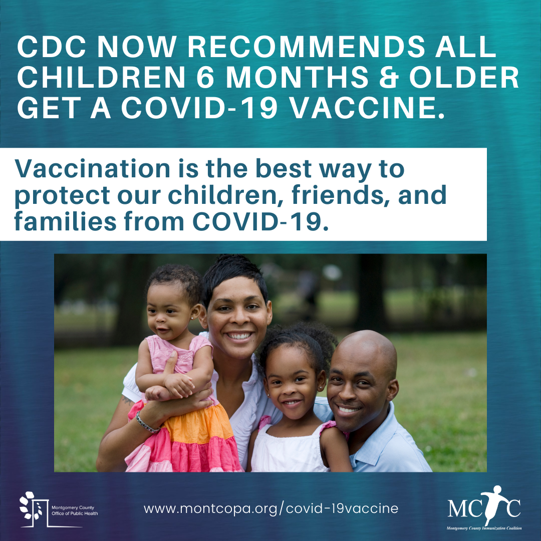 A Black family with two children smiling in a park.