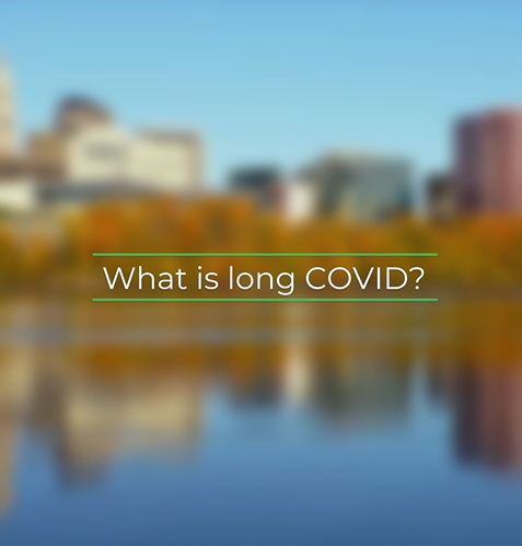 Centered white text that states "What is long COVID?" with green top and bottom border over a blurred image of a lake with autumn trees and buildings.