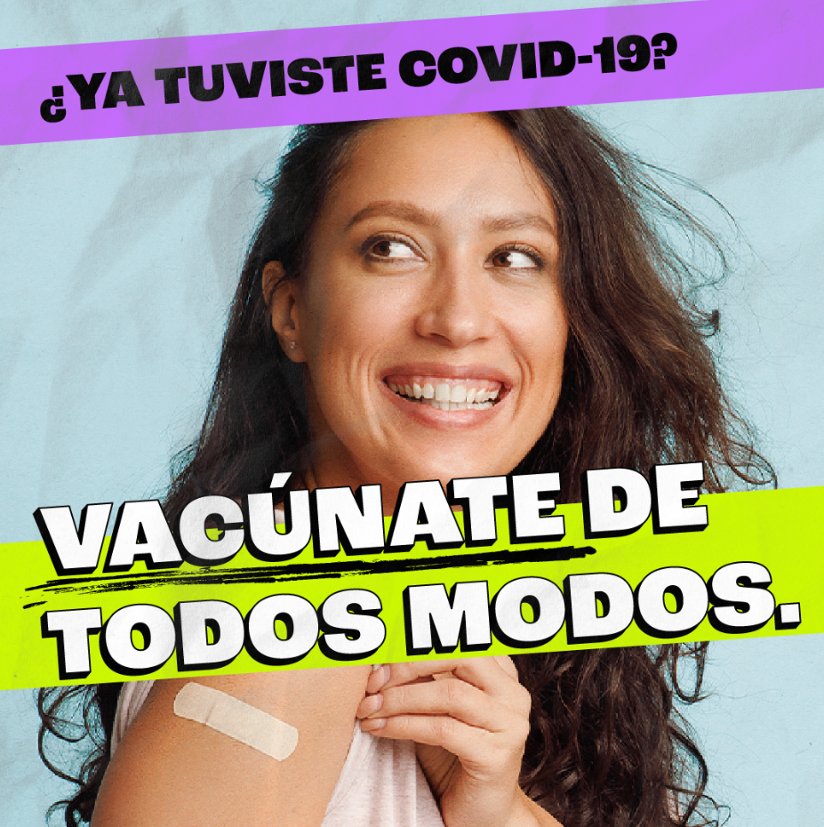 A person smiles while proudly showing a Band-Aid on her arm after getting vaccinated.