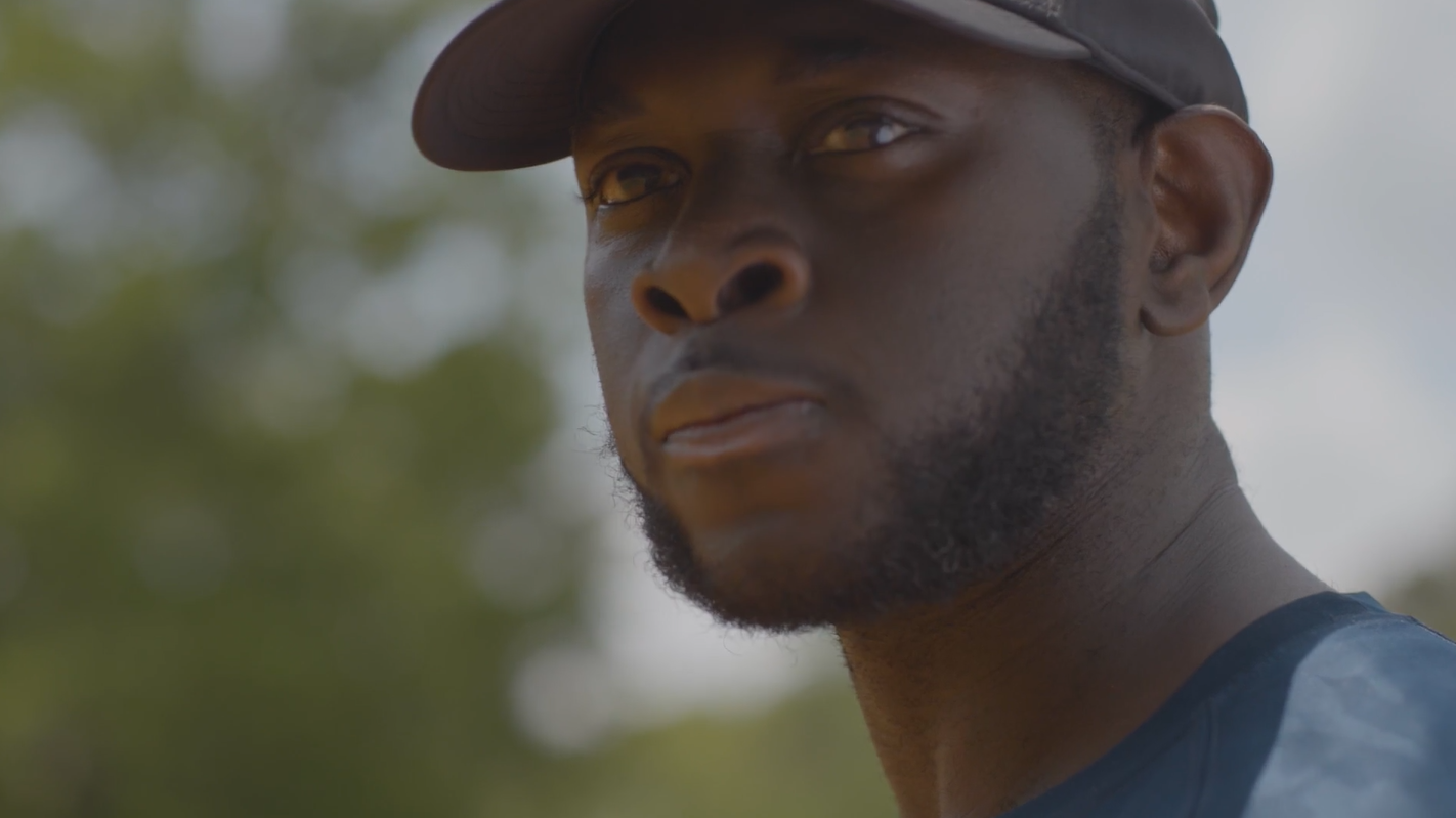 A Black man wearing a baseball hat and jersey. 