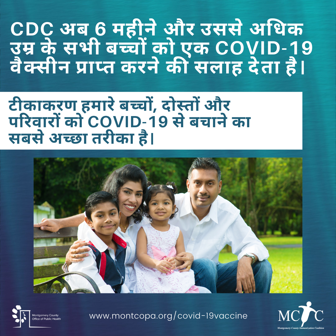 A South Asian family with two children smiling in a park.