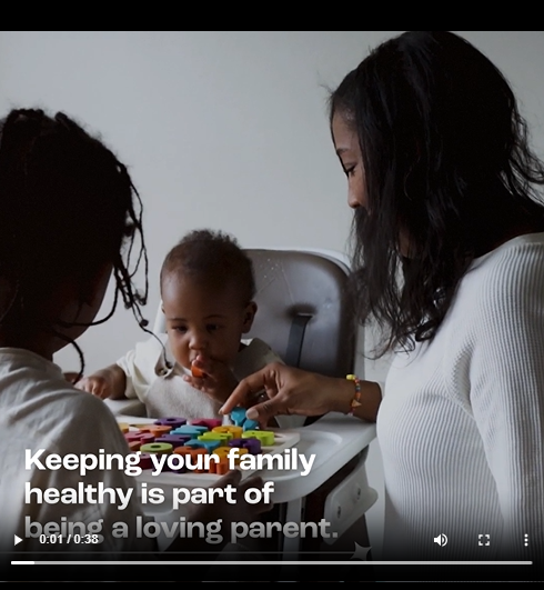 A Black mother and child play with infant sitting in high chair