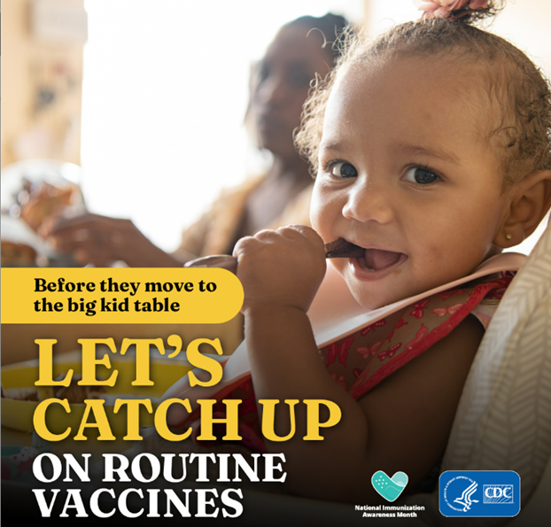 A baby girl with a pink bib around her neck chewing at the end of a fork. 