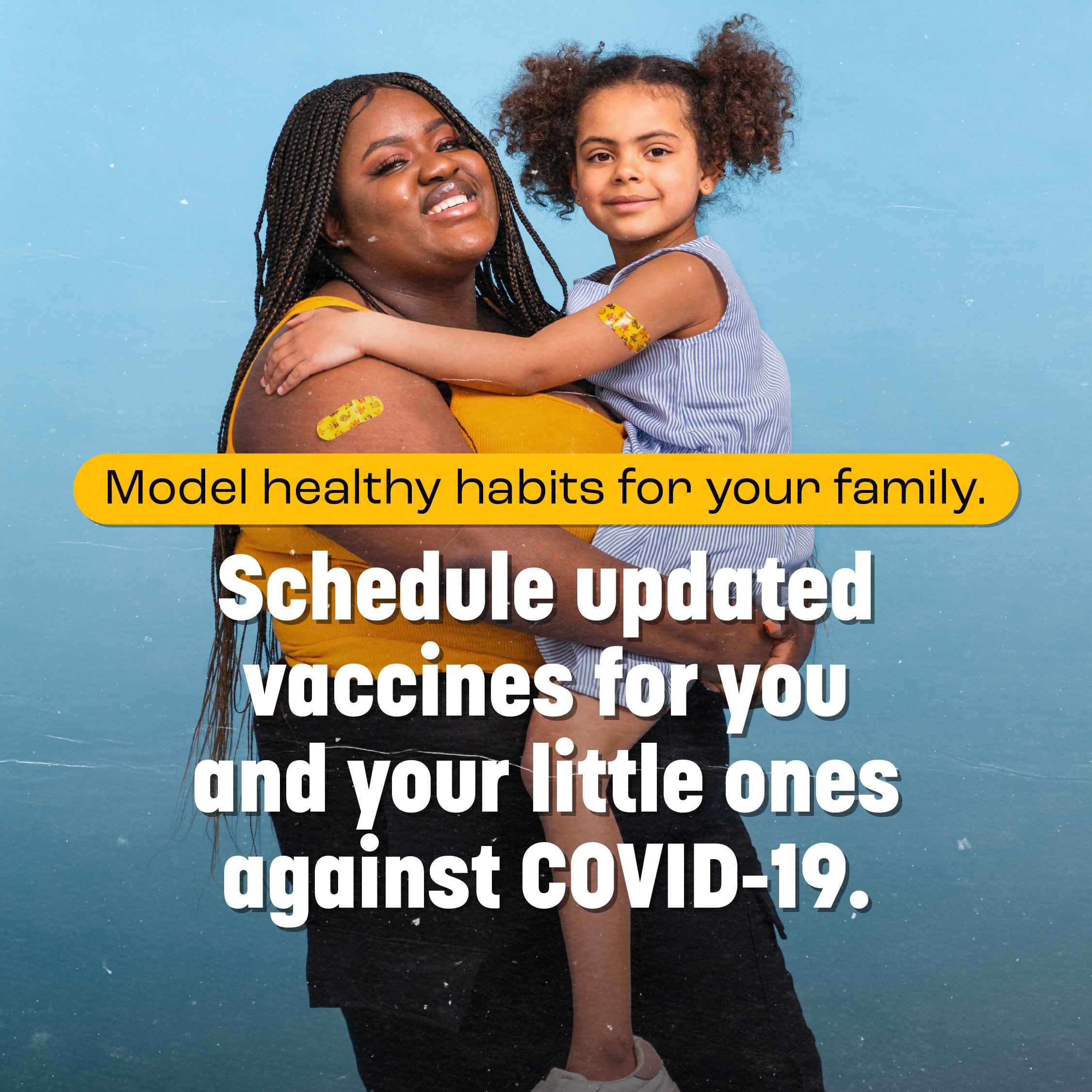 Image of a black woman with a bandage on her arm, smiling and holding a young black girl who also has a bandage on her arm