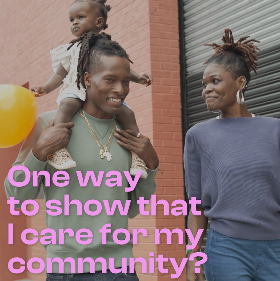Video still shows a Black family - mother, father and child - walking down the street, smiling.