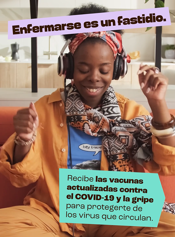 Black woman smiles broadly while dancing and listening to music on their phone.