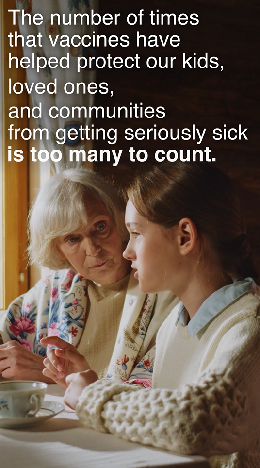 Video still shows a girl and her grandmother, sitting at a table together, looking out the sunny window, and talking over a cup of tea. 