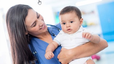 Image shows a white woman in scrubs smiling and holding a baby.
