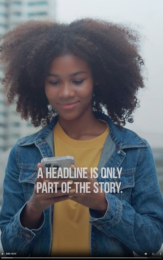 A young Black woman smiles and looks at her phone 